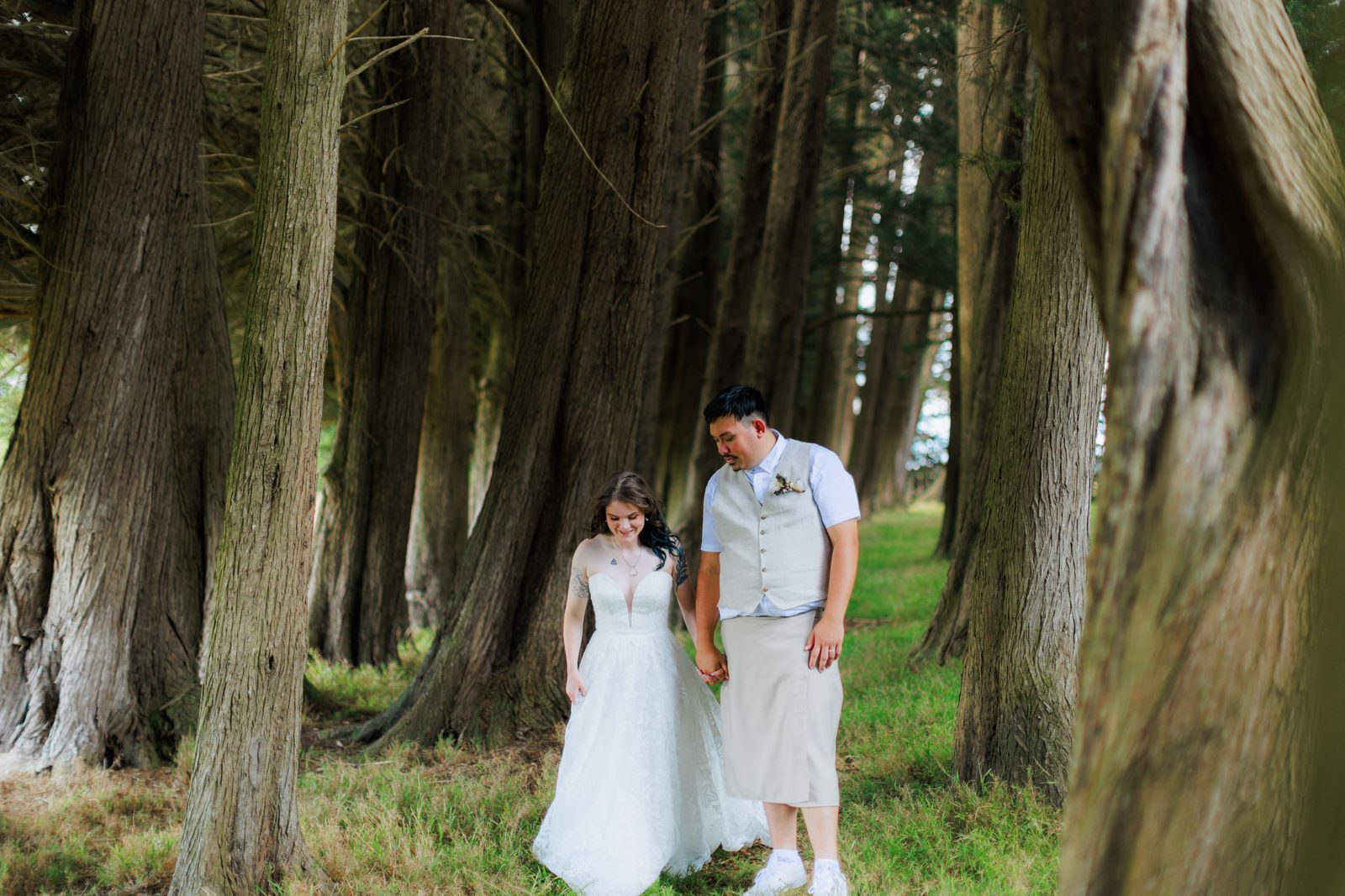 A wedding couple in the tree-lined grounds at Te Puna, a barn wedding venue near Feilding in the Manawatū